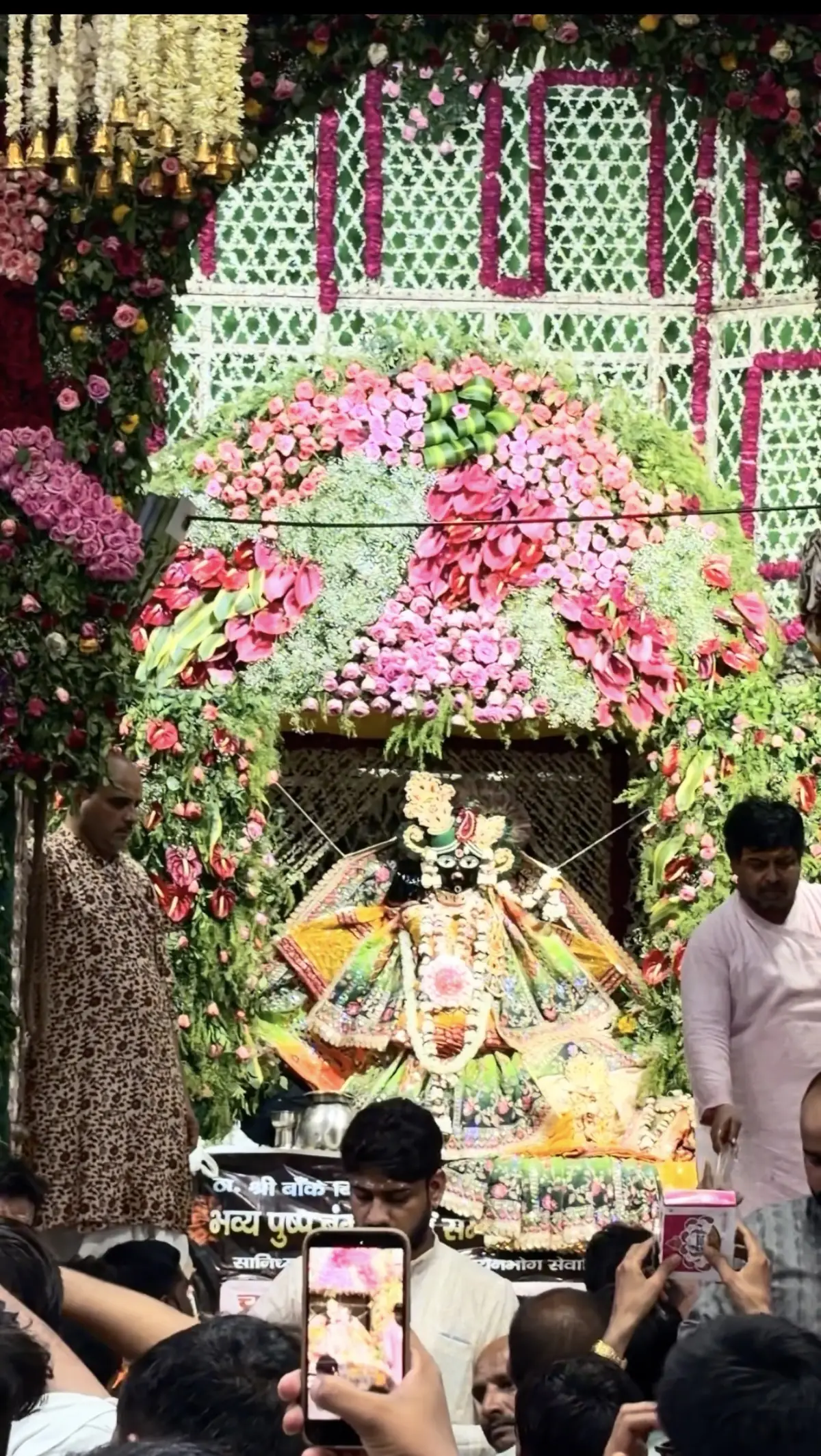 Shri Banke Bihari adorned in a colourful poshak beneath a grand phool bangla flower canopy at Banke Bihari Temple, Vrindavan