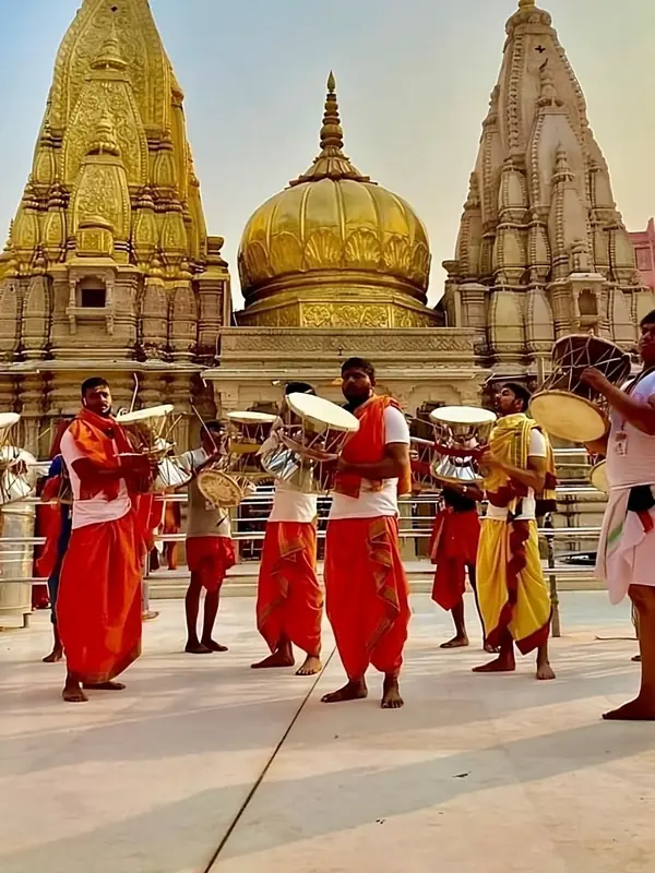Devotees playing the damru before the gold spires of Kashi Vishwanath Temple in Varanasi