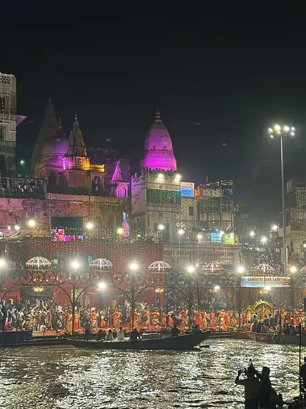 Evening Ganga Aarti at Dashashwamedh Ghat in Varanasi seen from a boat, with lit pink temple domes