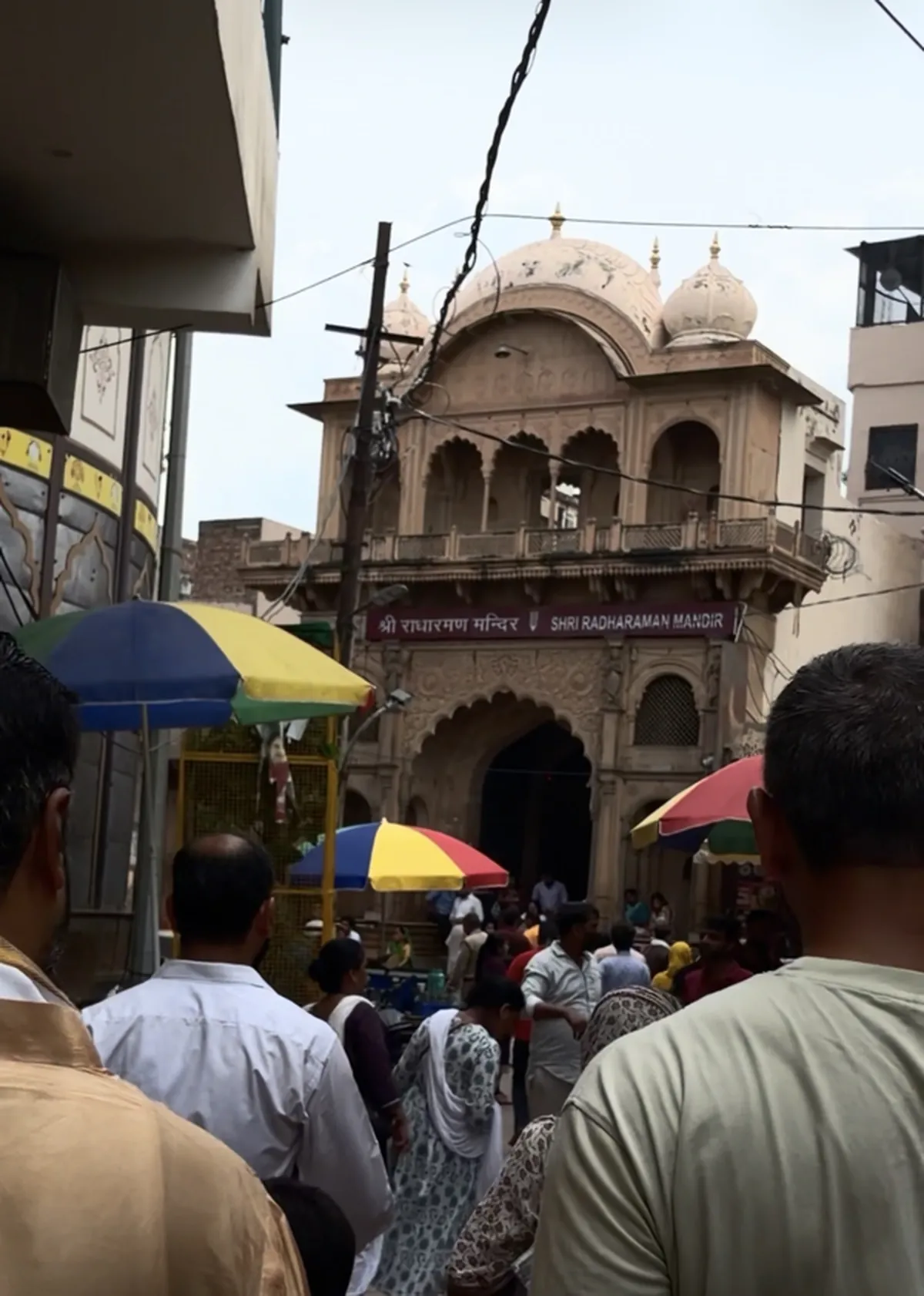 Devotees walking towards the carved sandstone gateway of Shri Radharaman Mandir in Vrindavan
